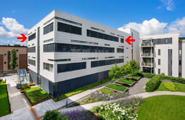 Modern apartment buildings with landscaped gardens under a blue sky.