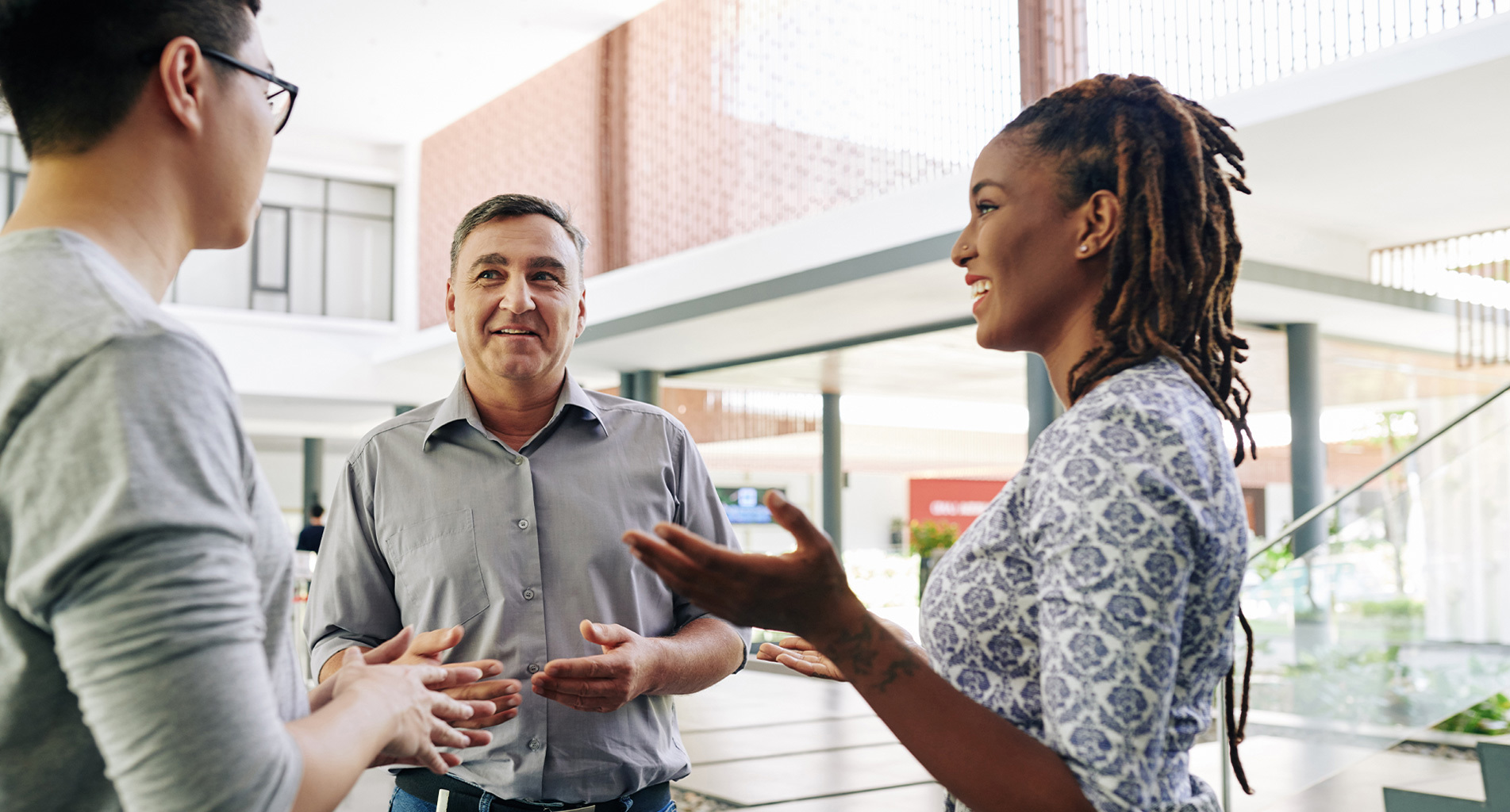 Three people having a conversation in a modern indoor setting.