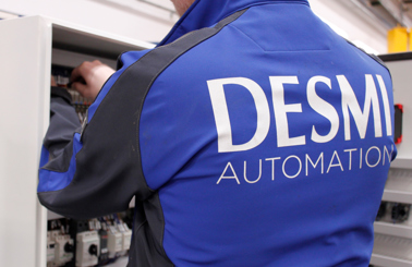 Person in DESMI Automation jacket working on electrical panel.