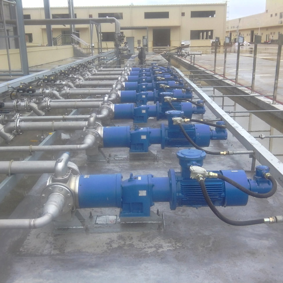 Multiple blue industrial pumps connected by pipes on a concrete platform.