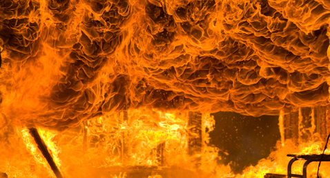 Intense flames engulf a structure, creating a dramatic inferno scene.