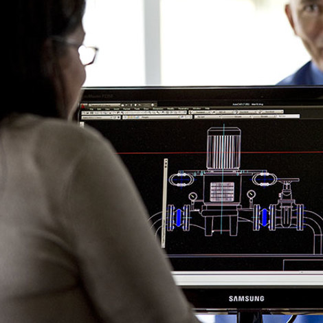 Two people discuss a technical design on a computer screen.