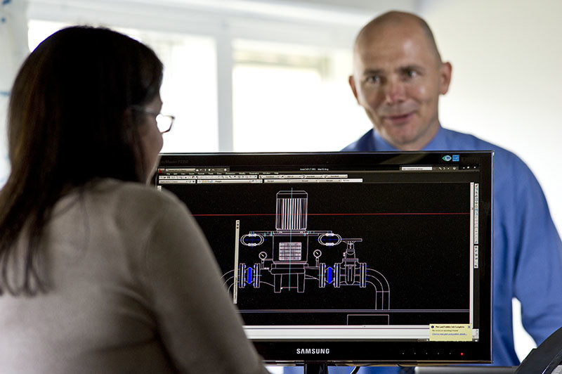 Two people discuss a technical design on a computer screen.