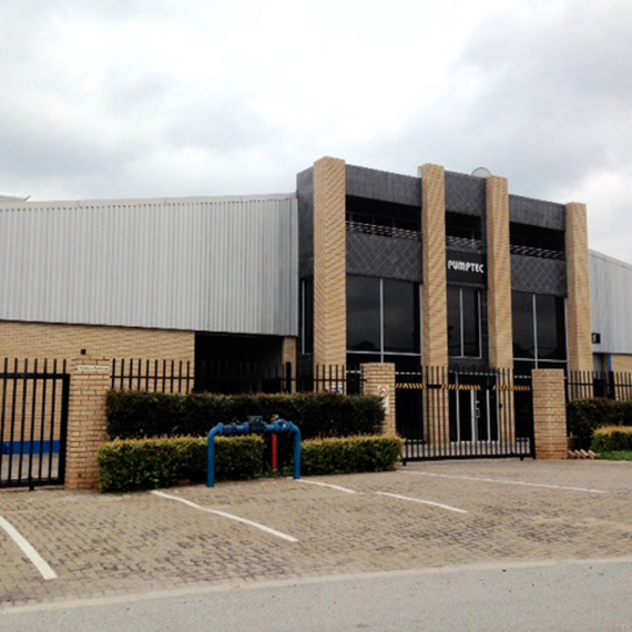 Industrial building exterior with brick facade and metal siding under cloudy sky.