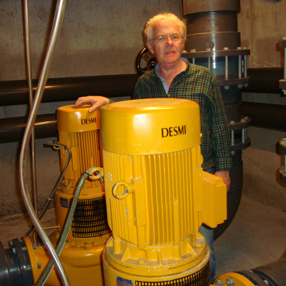 Man standing beside DESMI centrifugal pumps in an industrial setting.