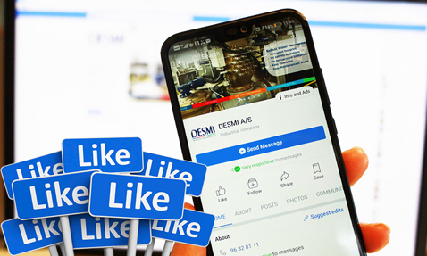 Smartphone displaying DESMI A/S Facebook page, surrounded by multiple "Like" signs.