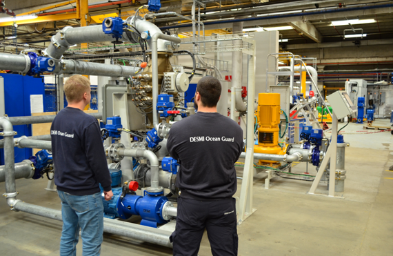 Two technicians inspect DESMI fluid handling equipment in an industrial facility.