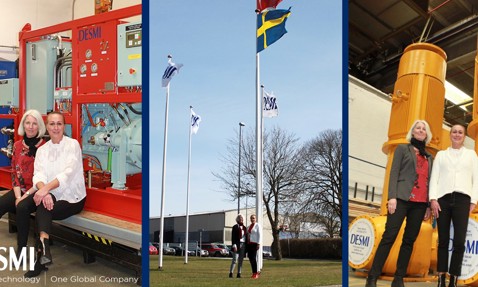 两位女性站在DESMI设备和旗帜旁，展示工业环境和技术。