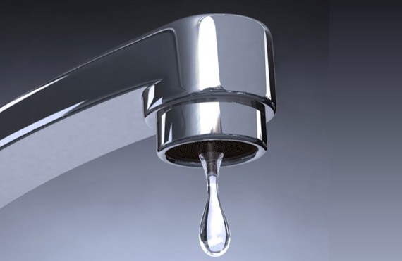 Chrome faucet with a single water droplet against a gray background.