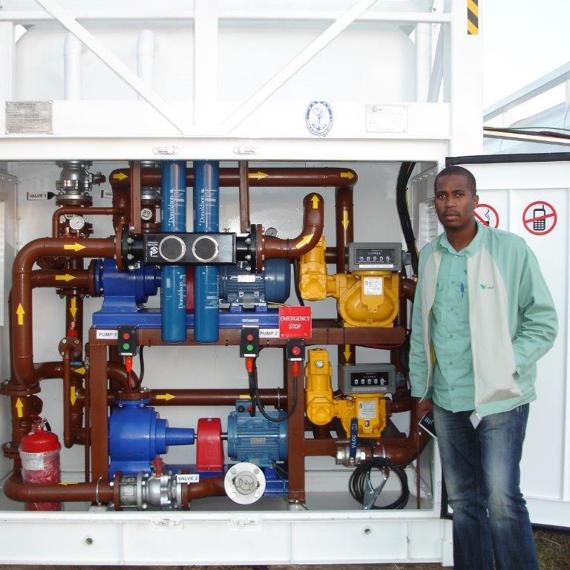 Person standing beside a DESMI pump system for fluid handling in an open cabinet.