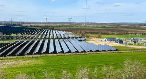 Solar panels and wind turbines in a green landscape, European Energy logo visible.