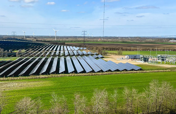 Panneaux solaires et éoliennes dans un paysage verdoyant, logo European Energy visible.