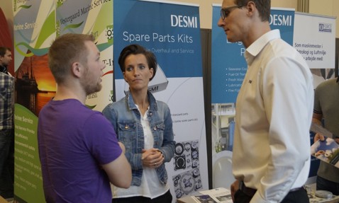 Three people discussing at a DESMI booth about spare parts kits.