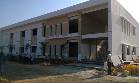 现代两层建筑正在施工，外面有工人和摩托车。