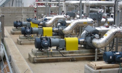 Industrial pumps and pipes arranged in a facility for fluid handling operations.