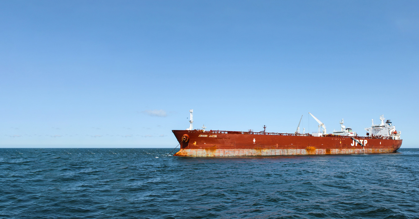 Large red cargo ship "Johann Jacob" on the ocean under a clear sky.