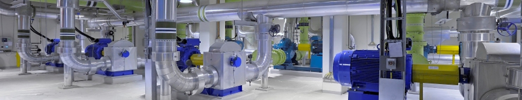 Industrial facility with blue and yellow pumps and extensive piping system.