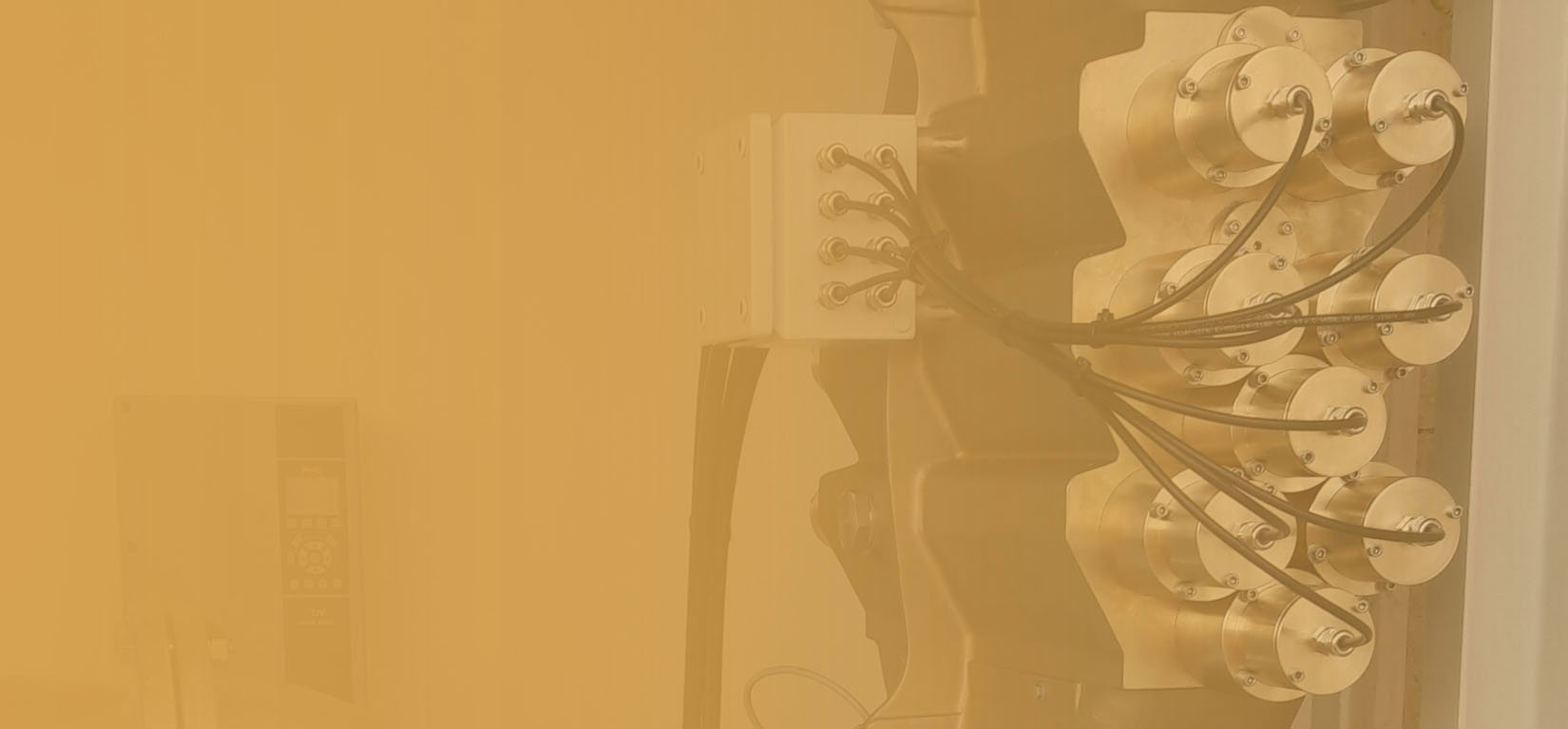 Industrial equipment with multiple cables and cylindrical components, partially obscured by yellow tint.