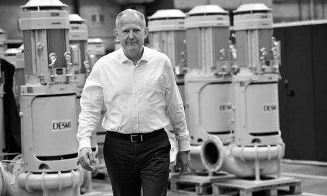 一名男子在工厂中行走，背景是DESMI泵。