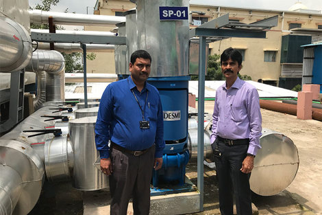 Two men standing beside a DESMI pump for fluid handling in an industrial setting.