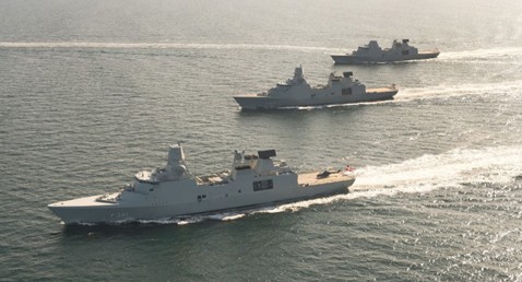 Three naval ships sailing in formation across open water.