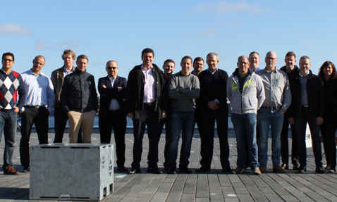 Group of people standing outdoors on a sunny day by the water.