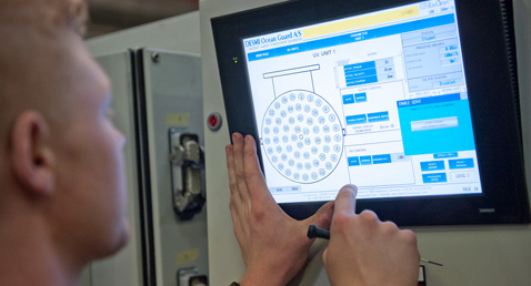 Person operating a DESMI Ocean Guard control panel for fluid handling systems.