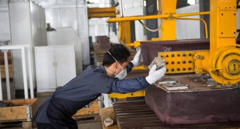 Worker wearing gloves operates machinery in an industrial setting.