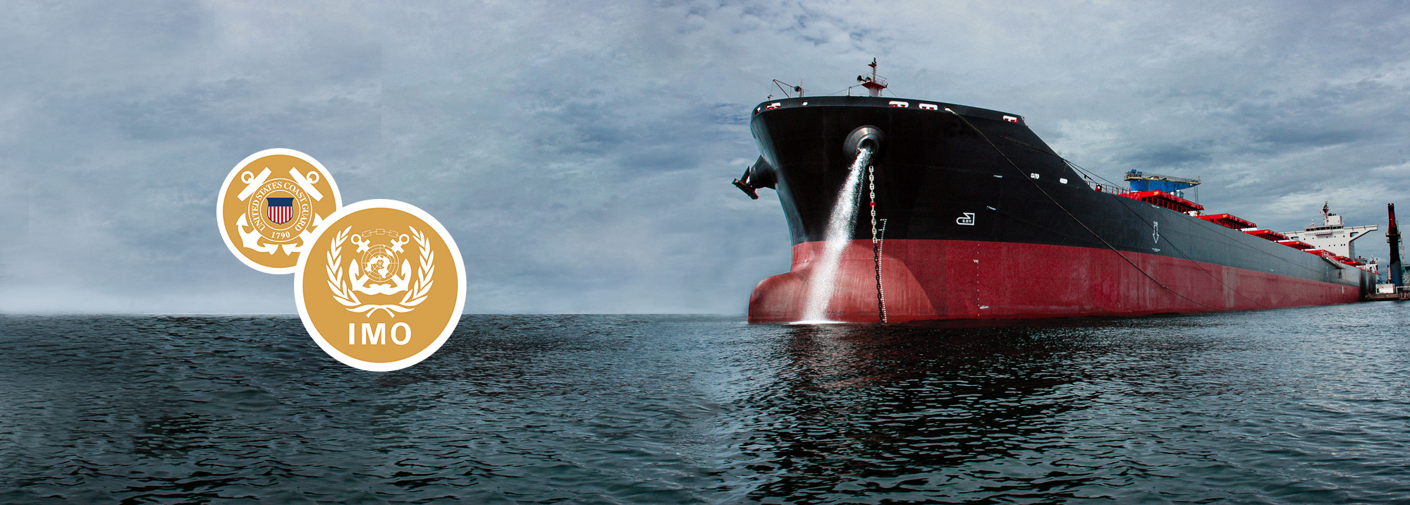 Large cargo ship in the ocean with United States Coast Guard and IMO logos.