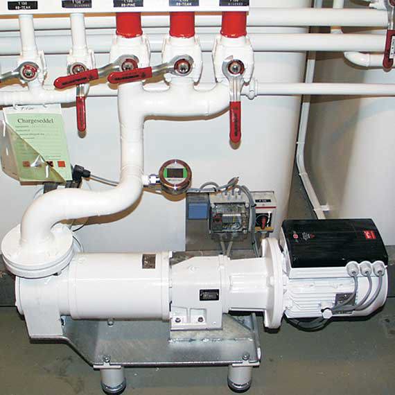 Industrial pump system with white pipes and red valves for fluid handling.