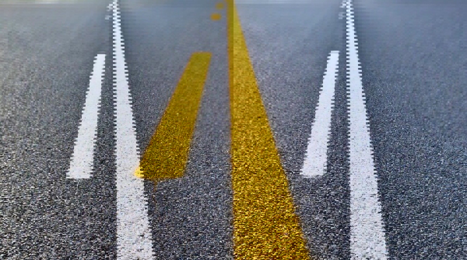 Close-up of a road with bright yellow center lines.