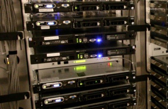 Rows of stacked servers with illuminated indicator lights in a data center.