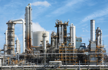 Industrial refinery with metal structures and pipes under a blue sky.