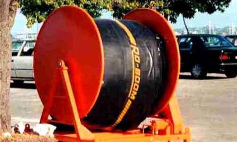 Large orange spool holding black hose labeled "RO-BOOM" in a parking area.