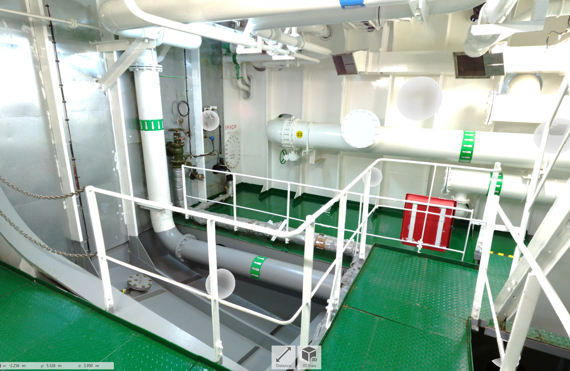 Industrial room with pipes and platforms, featuring green flooring and white railings.