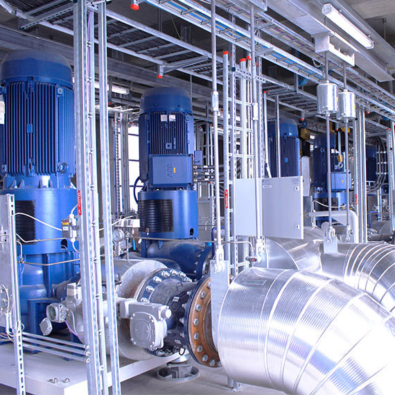 Sala industrial con grandes bombas azules DESMI y tuberías metálicas para el manejo de fluidos.