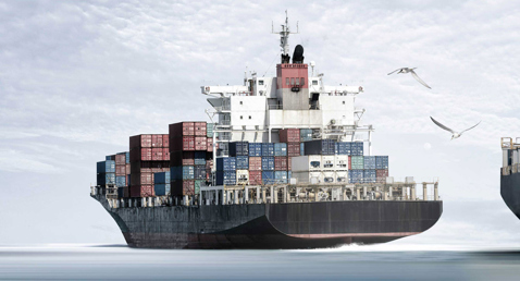 Large cargo ship loaded with colorful containers, sailing on a calm sea.