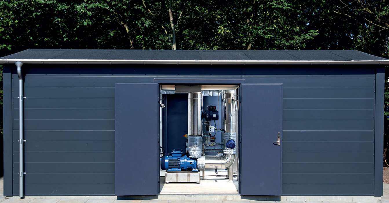 Small blue building with open doors revealing industrial pumps and pipes inside.