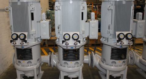 Three large DESMI vertical pumps with gauges, used for fluid handling applications.