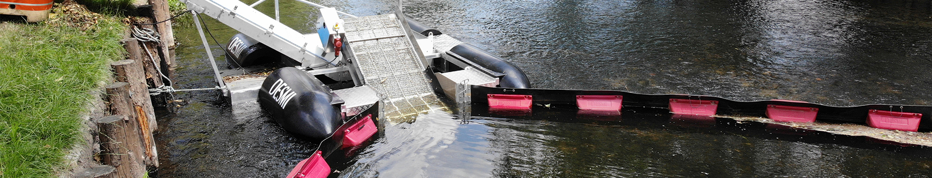 DESMI floating boom system deployed in a river for debris collection and containment.