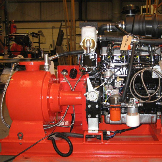 Red industrial pump system in a warehouse, featuring multiple hoses and components.