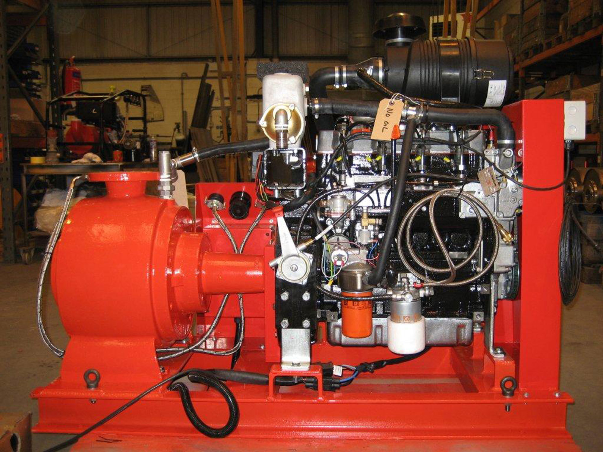 Red industrial pump system in a warehouse, featuring multiple hoses and components.