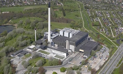 Aerial view of a large industrial facility surrounded by greenery and roads.