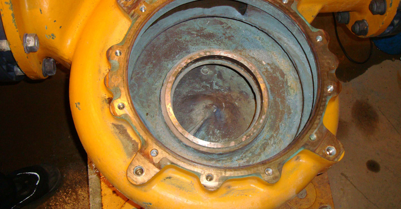 Yellow industrial pump housing with visible bolts and a central opening.