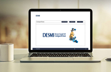 Laptop displaying DESMI Ocean Guard CompactClean system on screen, beside a coffee mug.