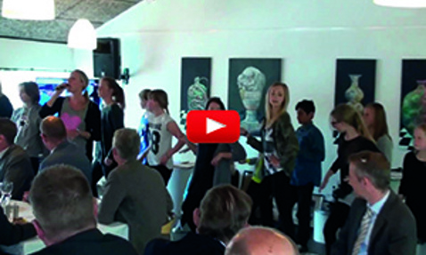 People gathered in a room, some seated, others standing and walking.