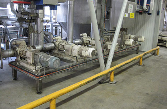 Industrial pumps and piping system in a facility, with safety barriers in place.