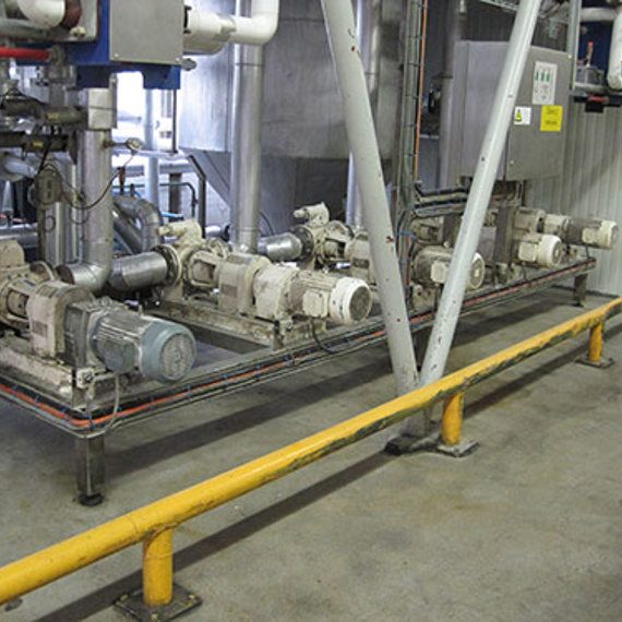 Industrial pumps and piping system in a facility, with safety barriers in place.