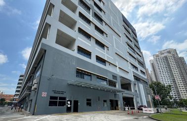 Modern multi-story building with geometric design and trees in foreground.