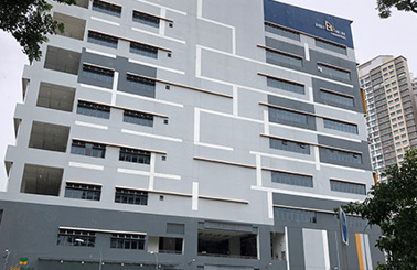 Modern multi-story building with geometric design and trees in foreground.